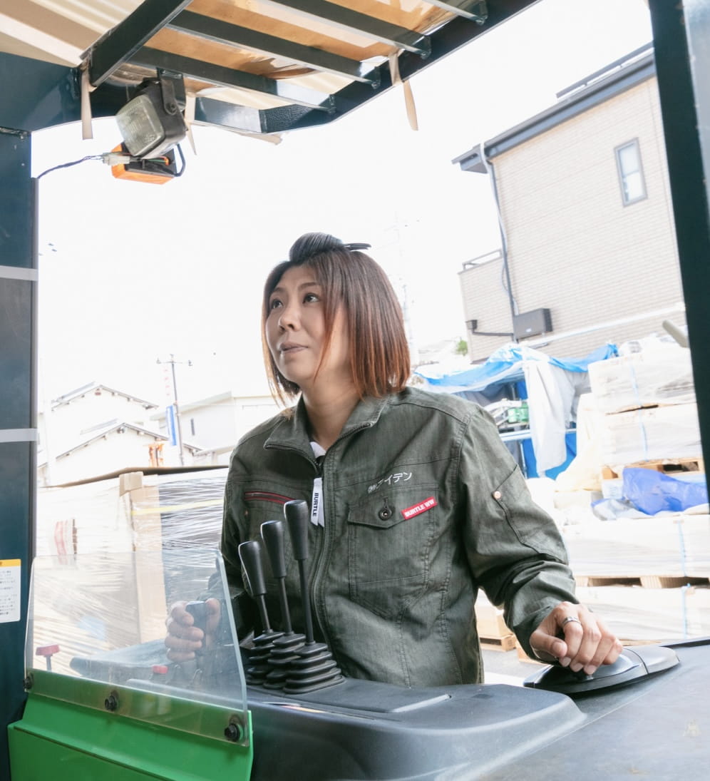 屋外の建築現場で作業に取り組む女性作業員の姿