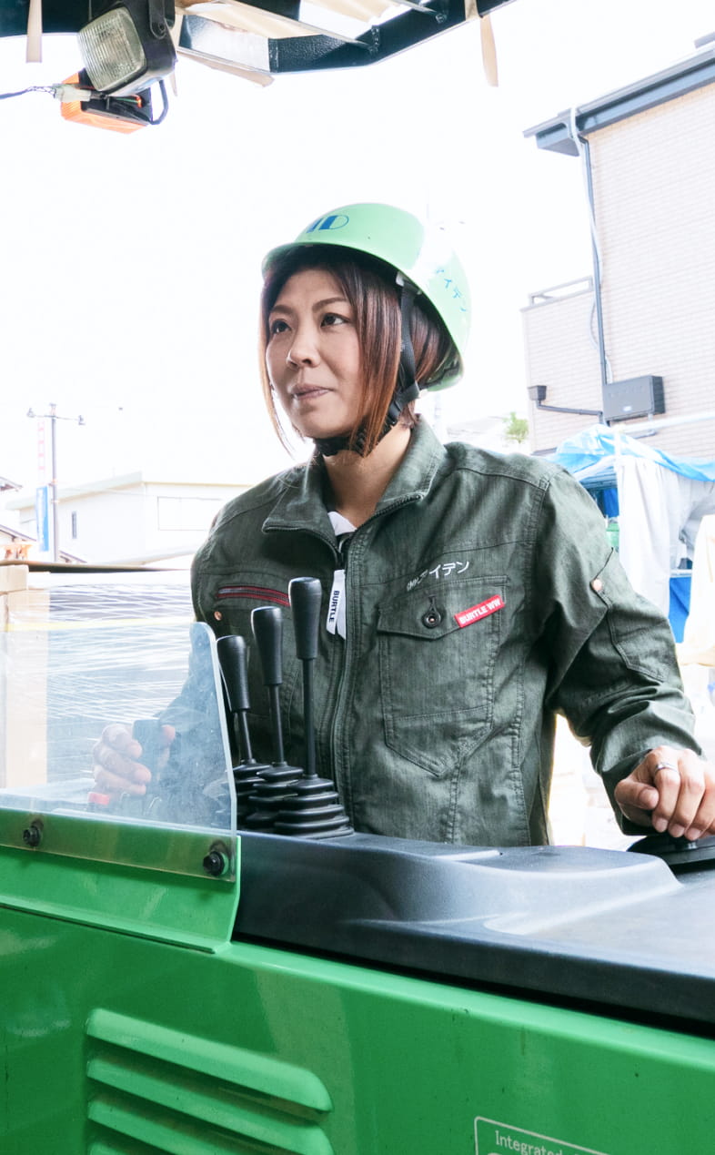 屋外の建築現場で作業に取り組む女性作業員の姿